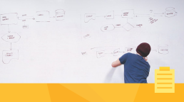 A man at a whiteboard working on improving workflow.
