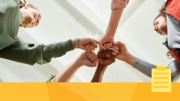 A photo of a group of people fist-bumping as they work on coming together as a team to discuss building a community for their journal.